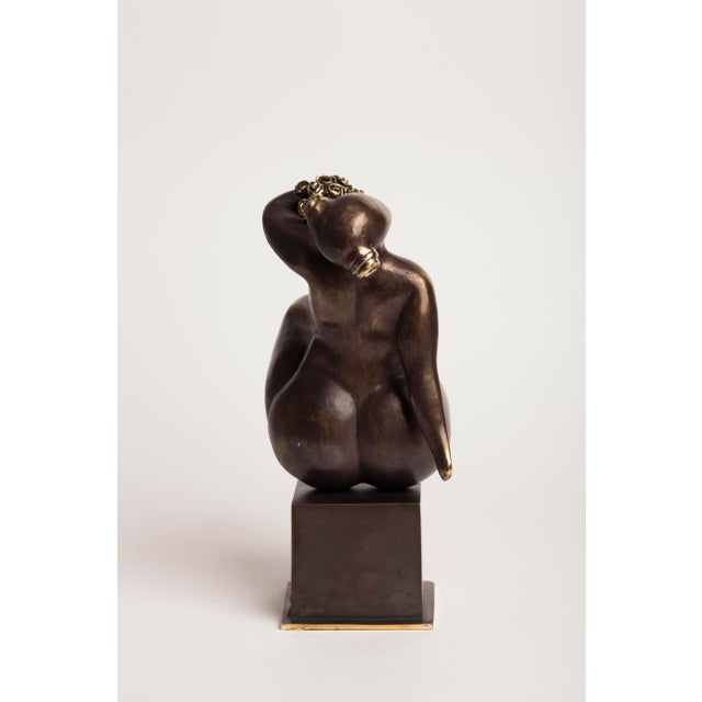 A contemporary figurative bronze of a seated woman, her form abstracted into long, fluid lines and resolved volumes. A...