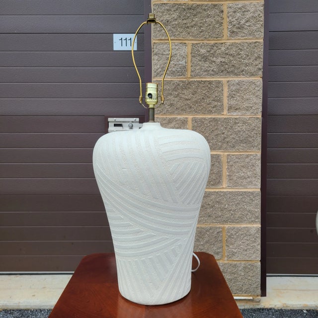A 1980s Postmodern white plaster table lamp with a raised pattern signed Bon Art (1986). Measures 22.5" from the base to...