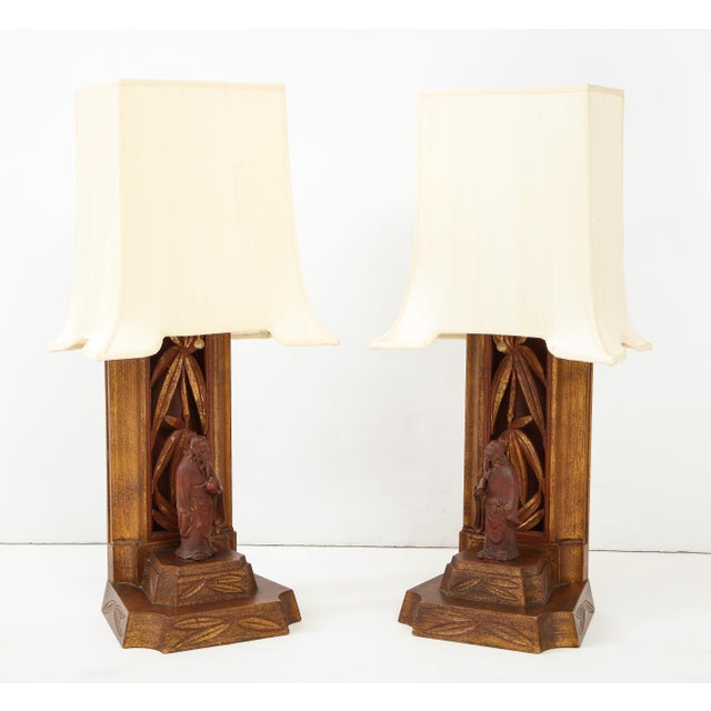 Wonderful pair of 1950s hand carved Chinese figurine lamps by James Mont. The cinnabar lamp bases and figurines are...
