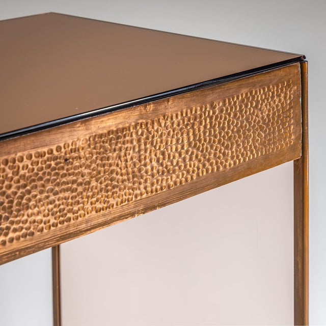 Small desk featuring a single drawer and a frame made of hammered copper with a crossbar stretcher. The desk stands on...