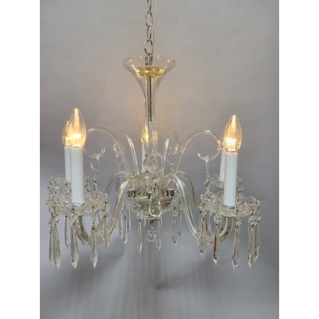 This lovely 5-arm chandelier features elegant Venetian-style scrolls and beautifully detailed crystal accents. Its...