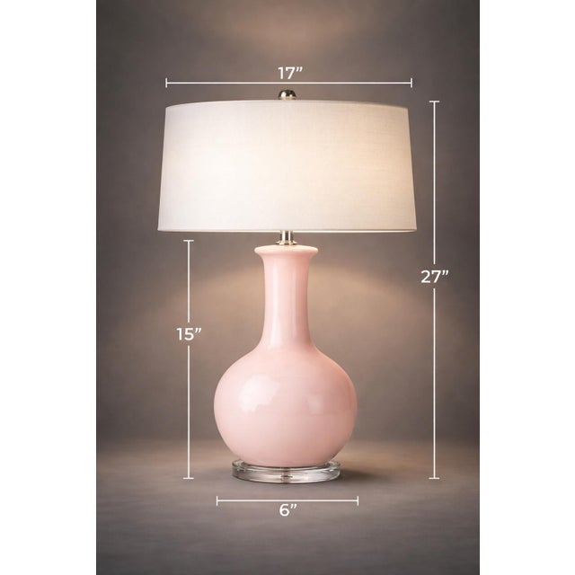 A refined blush pink glass table lamp with a sculptural gourd-form silhouette, elevated by a clear composite base and...