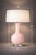 A refined blush pink glass table lamp with a sculptural gourd-form silhouette, elevated by a clear composite base and...