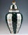 Very large urn-shaped vase with a lid; a bulging, tapered body standing on a flush stand with a straight, superimposed...