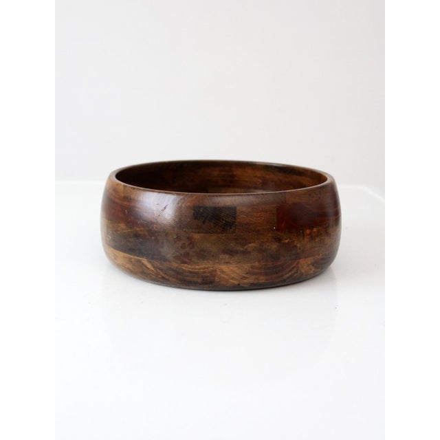 This vintage mid-century wood bowl features a low, rounded form crafted from joined sections of richly varied wood....
