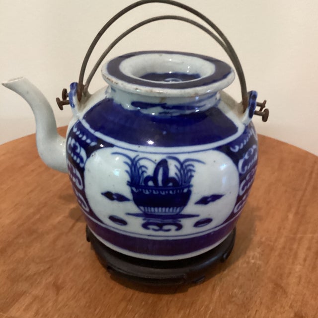 This antique Chinese export blue and white porcelain teapot with a wire bail handles hails from the Qing Dynasty era....