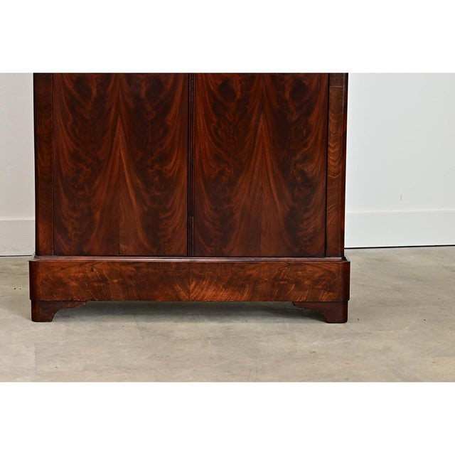 A modest yet spacious, 19th century French Louis Philippe style armoire handcrafted of mahogany with bookmatched doors...