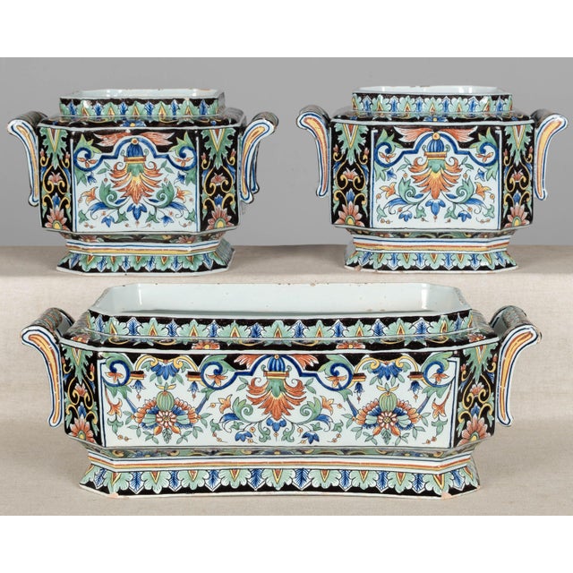 A set of three 19th century French polychrome painted faience planters, including a rectangular jardinière, and two square...