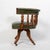 A banker’s swivel desk chair, featuring a rich green leather seat and backrest paired with beautifully turned oak...