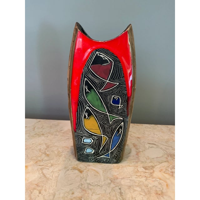 Multi-colored mid-century ceramic vase depicting fish in a riot of bright colors enveloped in realistic bark on three...