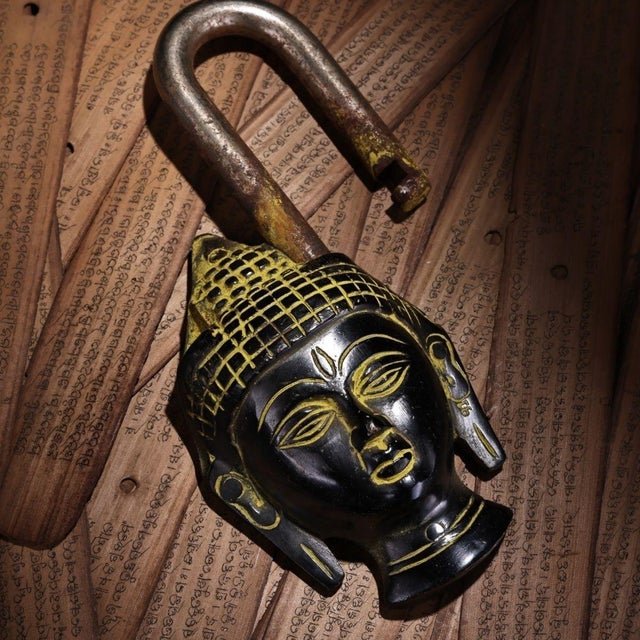 This is a striking and unusual vintage bronze padlock, crafted in the form of a serene Buddha head. The piece features a...