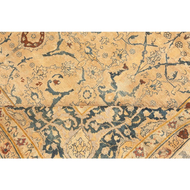An antique Persian Tabriz rug, hand-knotted in wool and dating back to circa 1920. This area rug exemplifies the...