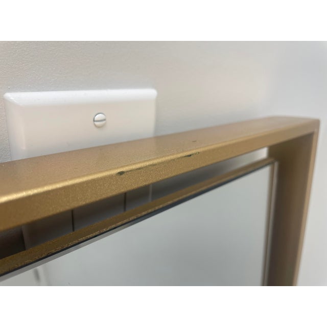 Contemporary mirror that is floating in the gold frame attached by black cleats. May be hung horizontally or vertically....