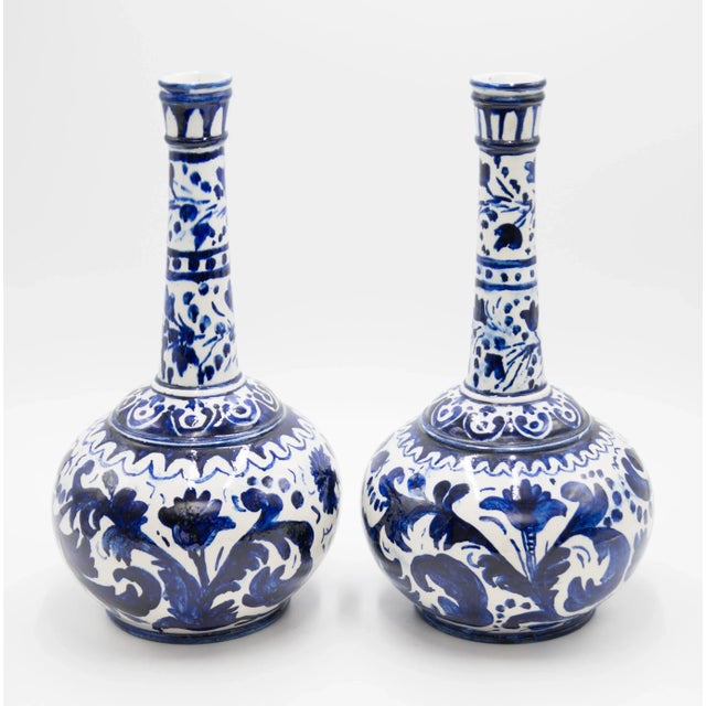 A fabulous vintage pair of European long neck bottle vases with hand painted floral designs in cobalt blue and white....