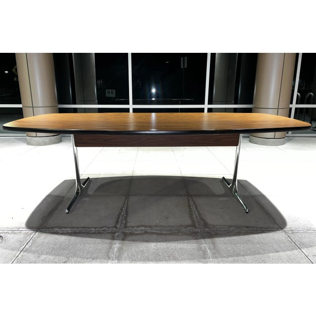 Early dining table having signature polished aluminum pedestal leg base and large 96” walnut veneer boat shaped top,...
