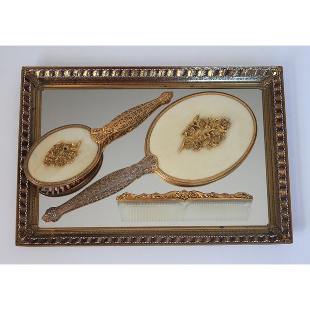 Vintage brass vanity set. The set includes mirrored tray, brush, comb, and hand mirror. Some light oxidation, age spots on...