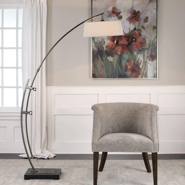 This floor lamp features an adjustable, large steel arc, finished in a plated, dark oxidized bronze, resting on a weighted...