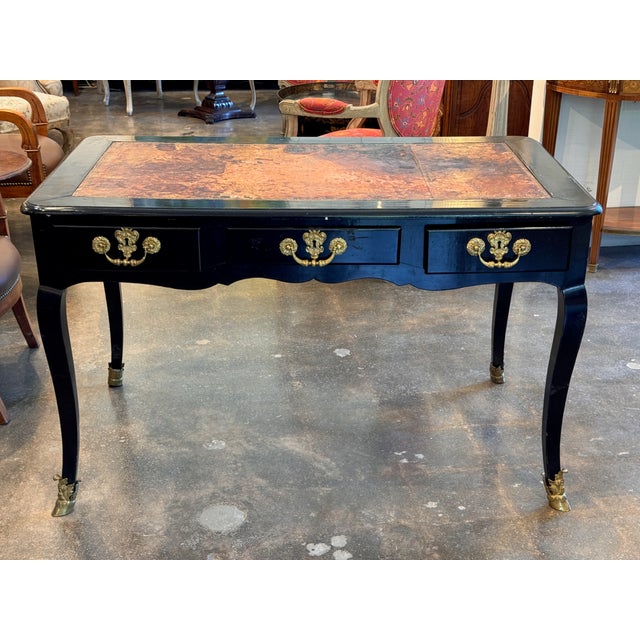 An elegant Early 19th Century French ebonized bureau plat with a warm, well-worn leather writing surface set within a...