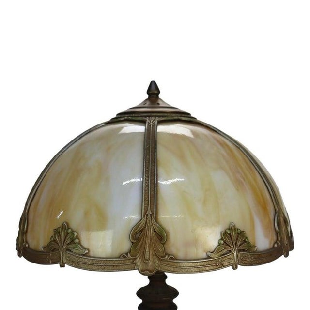 This antique table lamp, in the manner of Bradley & Hubbard, features a domed shade composed of six panels of variegated...