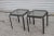 This is an outdoor end table with a metal frame and a glass top. The frame is black or dark gray with a tubular design,...