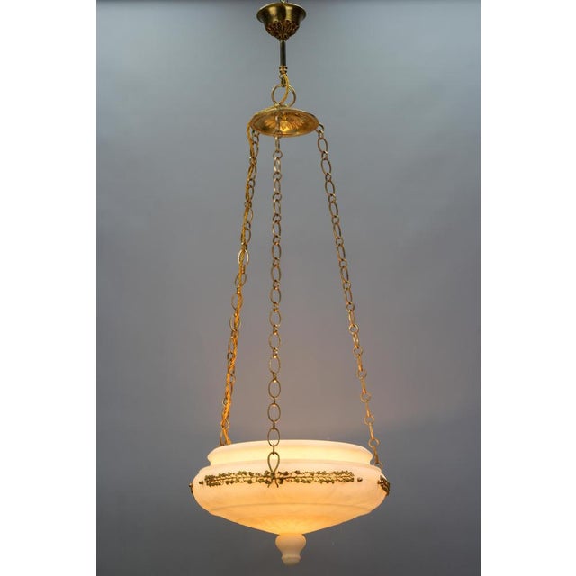 This impressive antique pendant light features a beautifully shaped carved white and ivory tone alabaster bowl hung on...