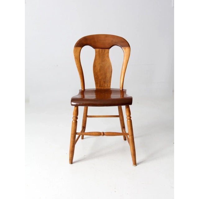 This is an antique balloon back dining chair. The classic Colonial style chair features a plank seat and turned legs.