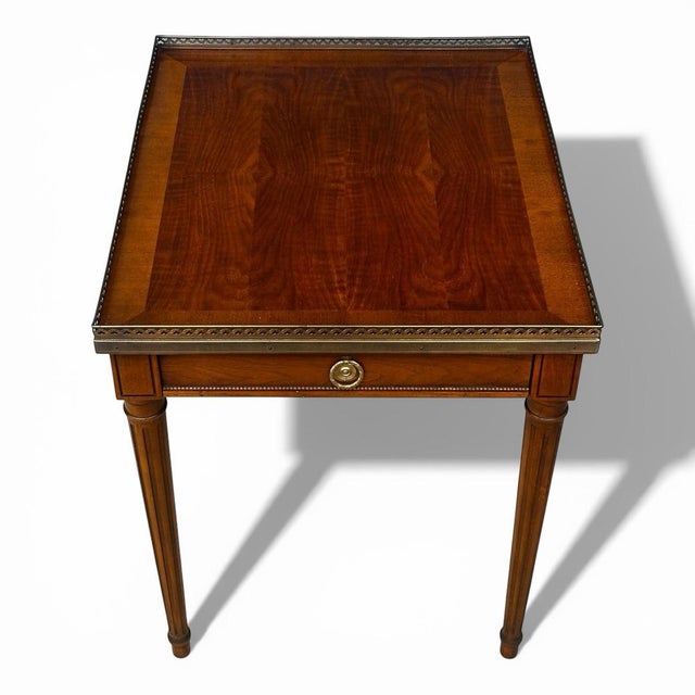 A beautifully tailored Baker Furniture Milling Road side table with a Louis XVI-inspired silhouette, warm figured walnut...