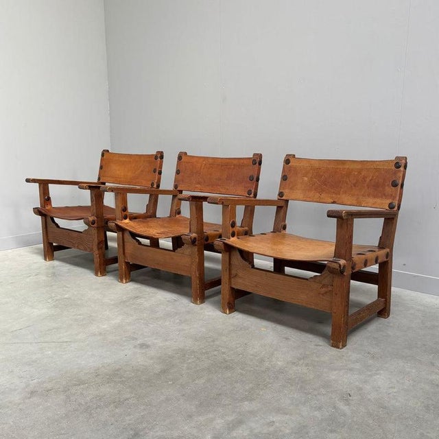 Remarks: Set Spanish arm chairs in brutalist style, 1960s. Solid oak frames with saddle leather seats. Chairs are good...