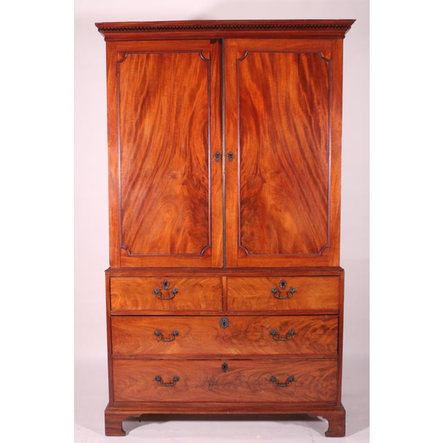 George III mahogany linen press, circa 1800. With a cove pediment with dental molding, two doors with nicely figured inset...