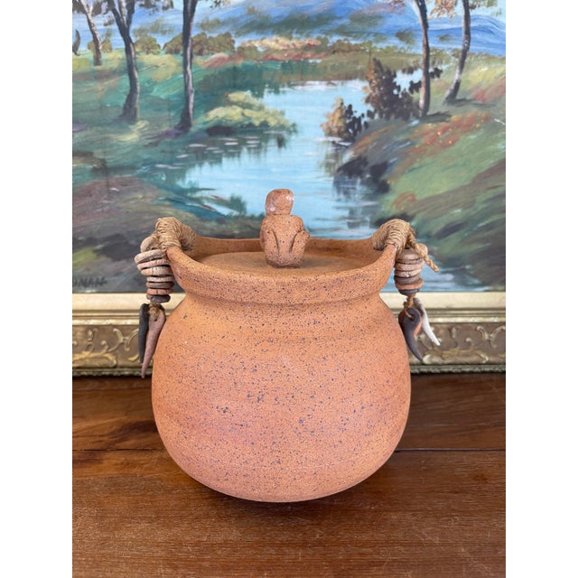 This handcrafted lidded jar originates from Indonesia and features a richly textured terracotta body with speckled surface...