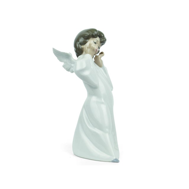 This charming vintage figurine by Lladró captures the serene essence of a young angel in a moment of peaceful reflection...