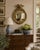 A Federal-style giltwood convex mirror crowned with a carved eagle, its wings outstretched above a laurel motif—an...