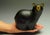 This bronze sculpture depicts a stylized black bear, its smooth, rounded form exuding a sense of warmth and playfulness....