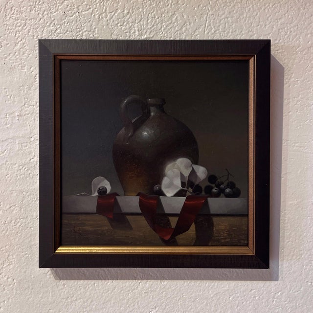 This oil on panel work features a meticulously rendered still life, highlighting a dark, textured jug alongside delicate...