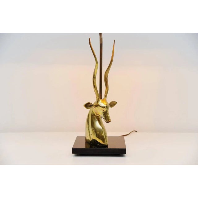 Very nice shaped deer head table lamp made in France, 1975. This lamp has a black lacquered wooden base and a brass...