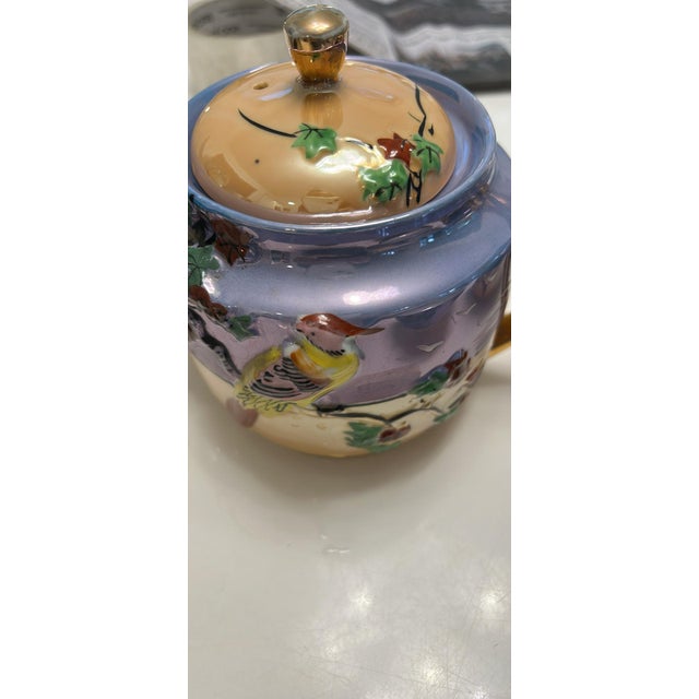 Elegant lusterware porcelain tea set with a hand-painted bird and landscape motif. This set includes a teapot with lid,...