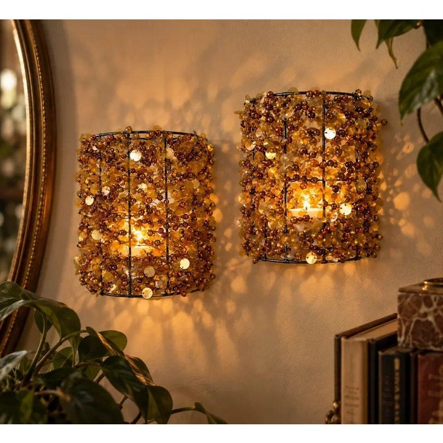 Striking vintage pair of Hollywood Regency amber beaded candle sconces featuring a densely layered arrangement of...