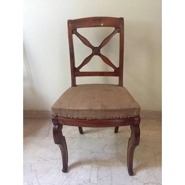 This set of five walnut chairs features a flower and cross decorated back, shaped legs, and original padding.