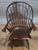 Chair has a bent back with rail arms ending in carved knuckles, spindles, carved saddle seat resting on tapered vase and...