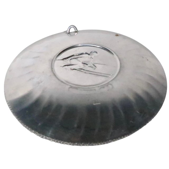 Aluminum souvenir plate depicting a downhill skier, made in Switzerland by Sigg. Executed in the Art Deco style - the...