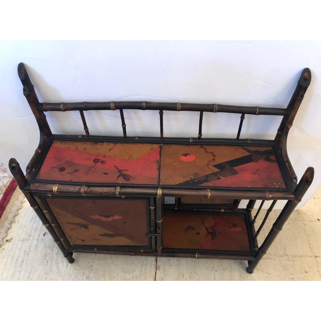 A gorgeous refined hanging shelf in black, gold, red and brown having bamboo structure and beautifully painted door and...