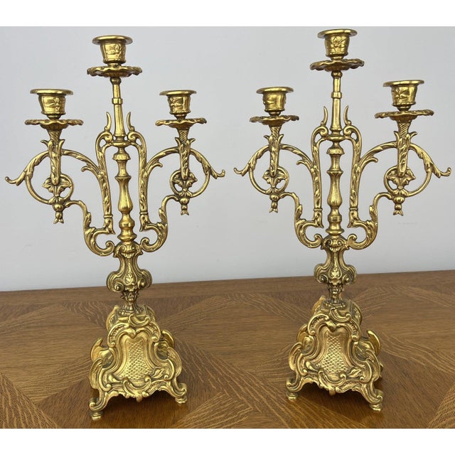 A beautiful pair of Vintage brass candelabras featuring an elegant three-arm design with ornate decorative detailing...