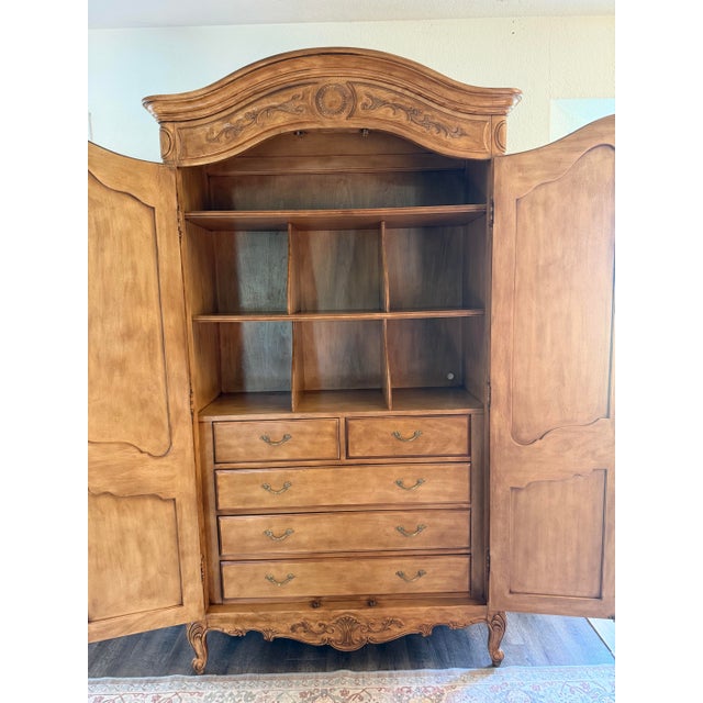 A substantial vintage Drexel Heritage armoire with elegant French Provincial styling, richly carved detailing, warm wood...