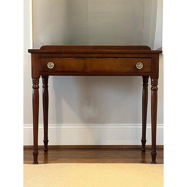 An attractive antique cherry side table from New York State. The side table has a rectangular top, above a single frieze...