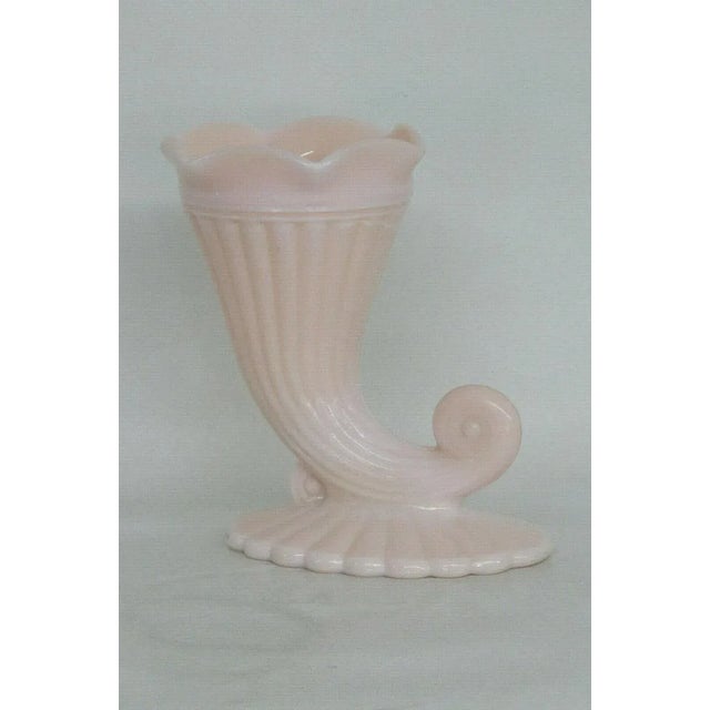 This adorable small vase is made of glass. This cornucopia vase has a fabulous opaque pink color to the milk glass, a...