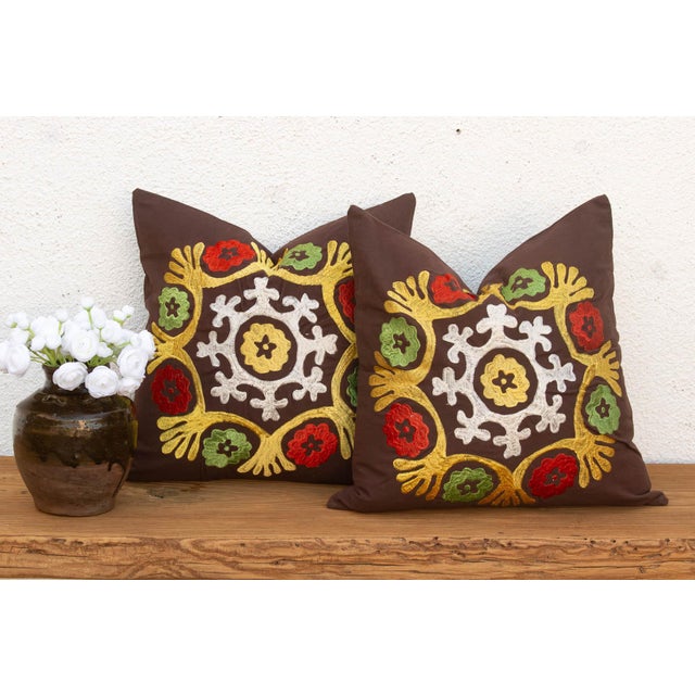 A radiating medallion in mustard-gold, worked as stylized wing-like forms reaching outward, frames a cluster of red flower...