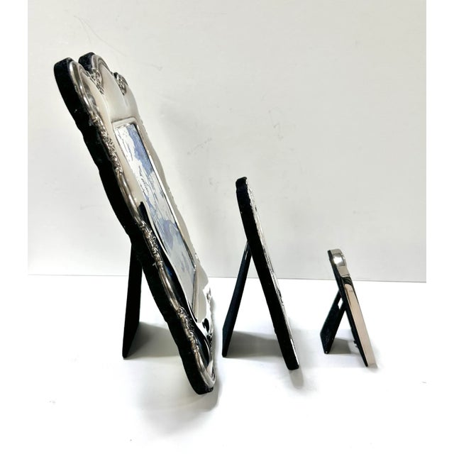 A decorative trio of embossed silver-plate picture frames featuring classic repoussé detailing and black velvet backs. The...