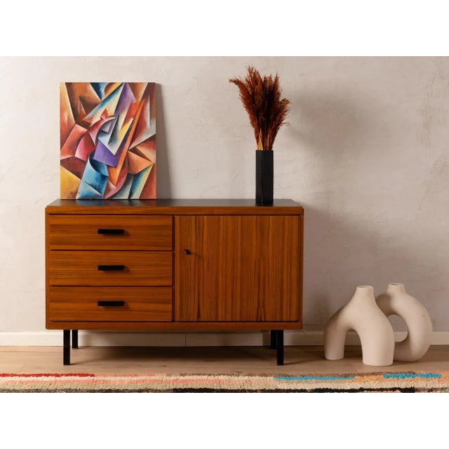 Classic chest of drawers from the 1960s. Corpus in teak veneer with four drawers, one door, one shelf and tapered feet....