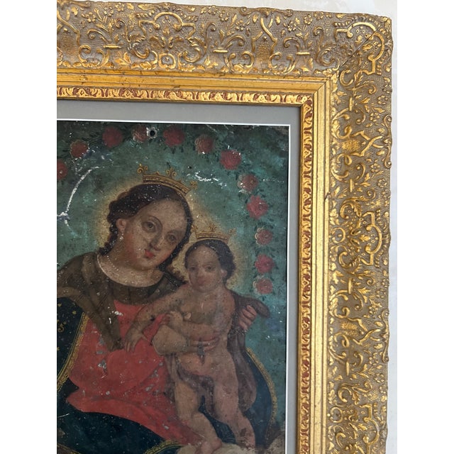 Antique Spanish Colonial retablo of the Virgin Mary and baby Jesus framed by red roses, they are both wearing crowns and...