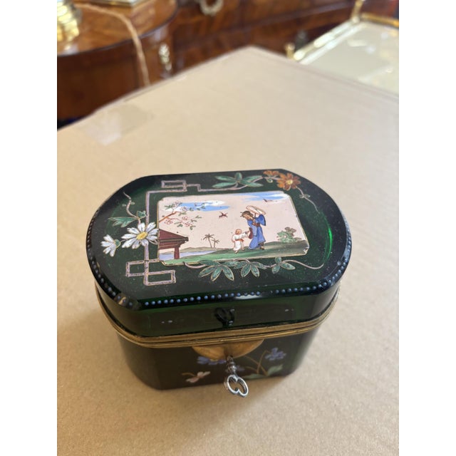 An exceptional antique lidded box made of green glass with delicate hand-painted enamel decoration. This decorative box...
